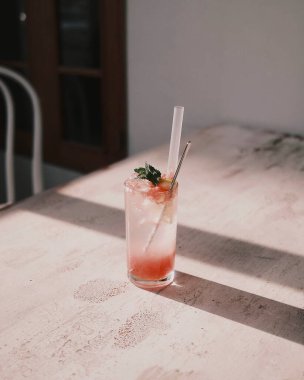 Tahta bir masada buzlu ve naneli bir bardak taze meyve suyu.