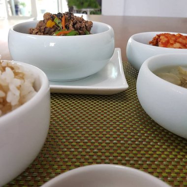 Tavuklu ve sebzeli bir kase pilav beyaz masada.