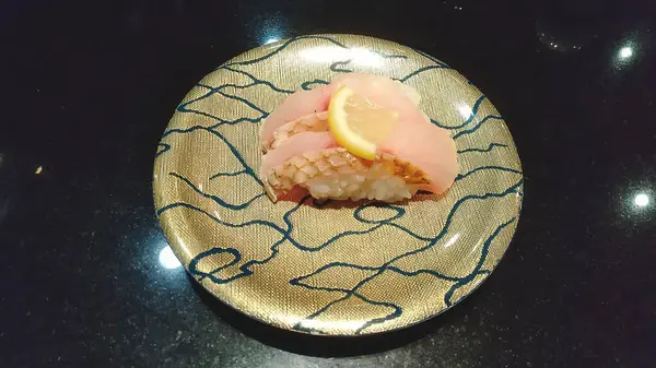 Somonlu suşi ve siyah tabakta sebze.