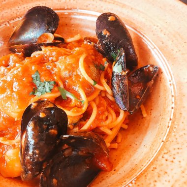 Restoranda beyaz tabakta deniz ürünleri soslu spagetti.