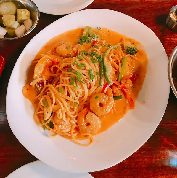 Karıştır - ahşap masada beyaz bir kasede baharatlı soslu kızarmış karides eriştesi..