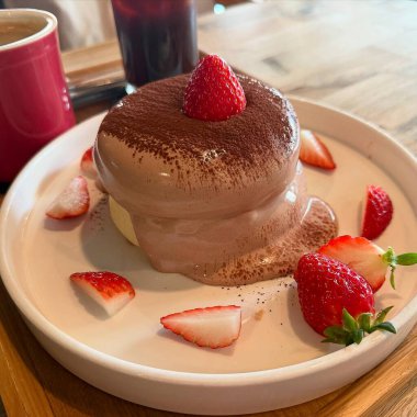 Çikolatalı dondurma, ahşap bir masada çilekli.