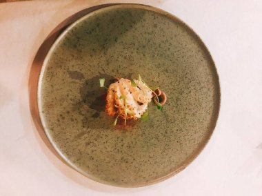 Tabağında yeşil bir yaprak olan beyaz bir tabağın yüksek açılı görüntüsü.