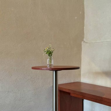 Bir vazonun dikey yakın çekimi, bir bardak suyla ahşap bir masanın üzerinde.