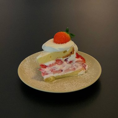 Kremalı çilekli pasta ve beyaz tabakta nane yaprağı.