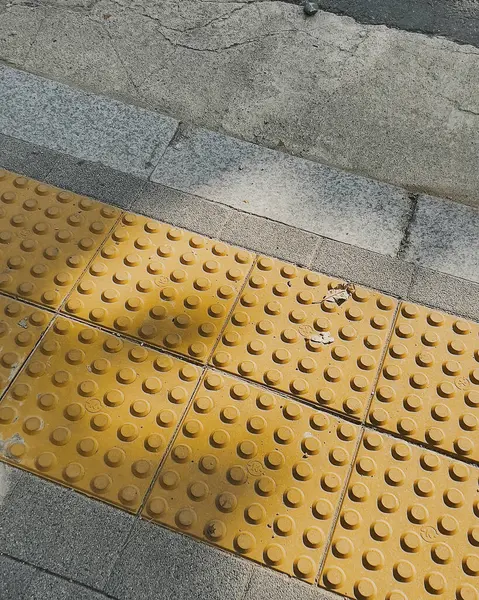 Sokakta sarı ve gri fayanslar.