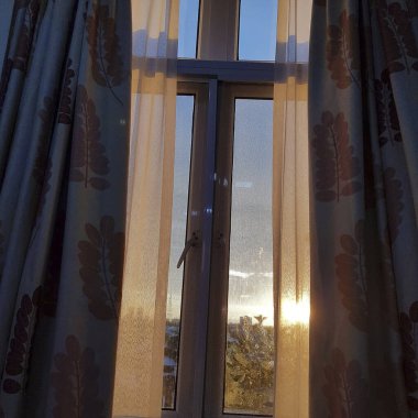 Beyaz perdeli bir otelin penceresinden manzara.