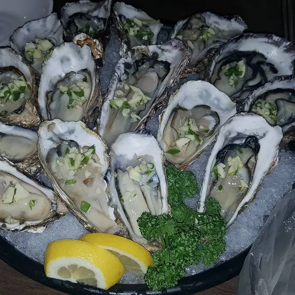Limonlu taze midye ve siyah tabakta maydanoz.