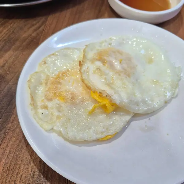 Yumurtalı pilav ve beyaz tabakta kızarmış yumurta.