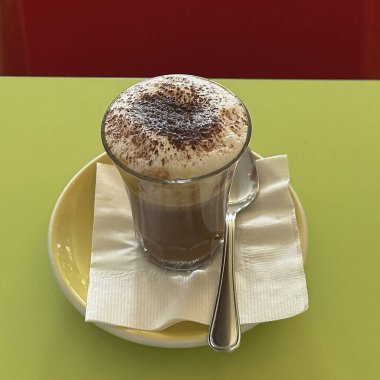 Kahve dükkanında beyaz bir masada beyaz bir fincanda kapuçino.