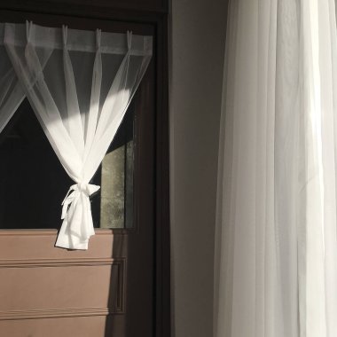 Yatak odasının iç kısmında beyaz perdeler olan pencere..