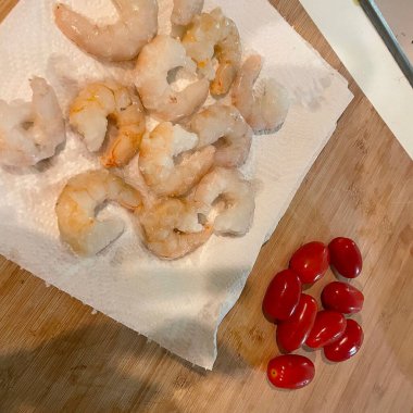 Tahta bir masadaki tabakta kırmızı ve beyaz karides ve domates.