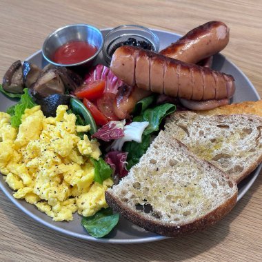 Yağda yumurta ve pastırma, ekmek, domates, salatalık, salatalık, marul ve pastırmalı ekmek ve tost ile nefis bir kahvaltı.