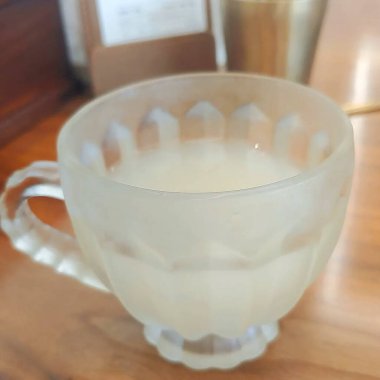 Beyaz arka planda kaşığı olan bir fincan kahve.