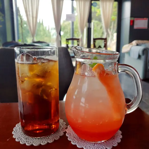 Cam kavanozda buzlu çay ve masada fincan.