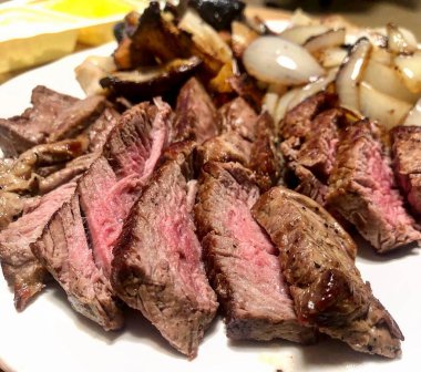 Sebzeli ızgara biftek ve beyaz tabakta otlar.