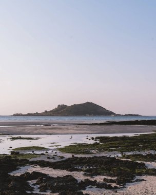 Temiz bir gökyüzünün altında, sahildeki boş kumlu bir sahilin dikey görüntüsü.