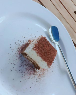 Tahta bir masada beyaz bir tabakta çikolatalı pasta.