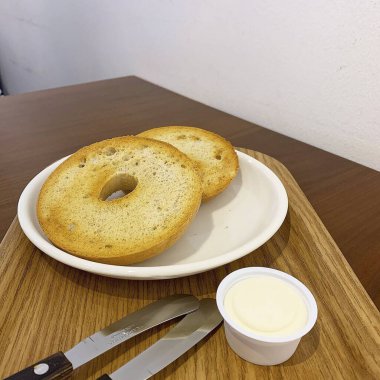 Beyaz bir fincanın yüksek açılı görüntüsü, siyah bir tabak tereyağlı sandviç.