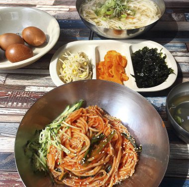 Kore mutfağı. Tahta masadaki kasede sebze ve sebzeli erişte.