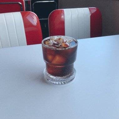 Bir fincan buzlu kahve ve beyaz arka planda bir kaşık.