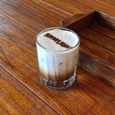 Tahta arka planda pipetle bir fincan sıcak kokteyl.