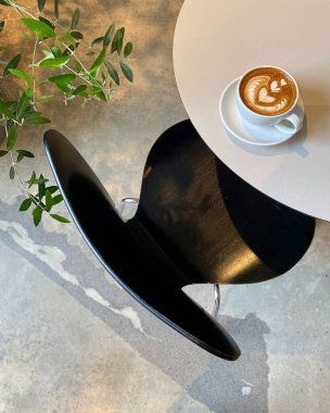 Bir fincan kahve ve masada siyah bir kupa.