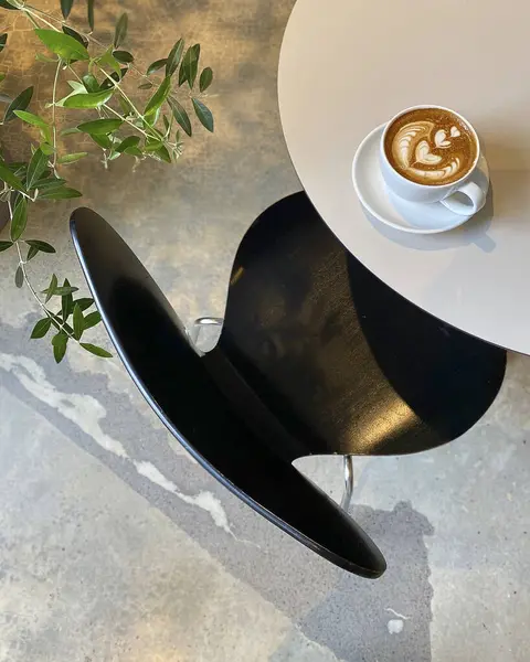 Bir fincan kahve ve masada siyah bir kupa.