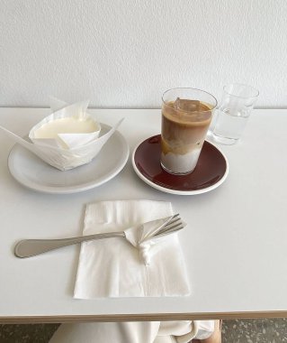 Bir fincan kahve, kaşık ve beyaz bir masada bıçak.