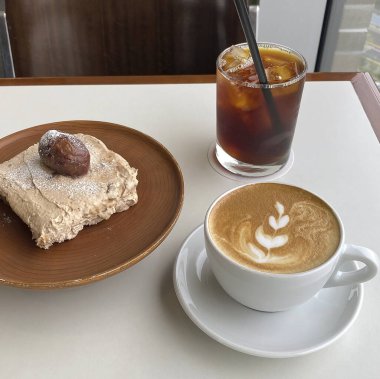 Çikolatalı kekle bir bardak kahve ve tahta bir masada bir fincan kahve..