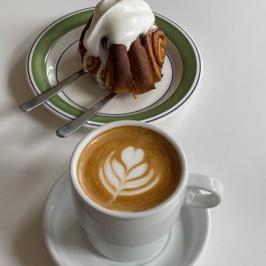 Bir fincan kapuçino ve beyaz tabakta çikolatalı kek.