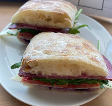 Domatesli bir tabağın üzerindeki sandviçin yakın plan fotoğrafı.