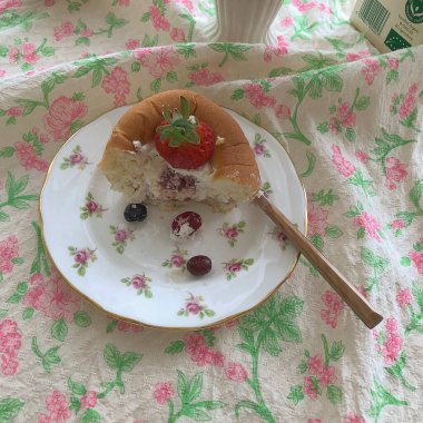 Bir fincan çayla bir parça kek ve beyaz tabakta kaşıkla bir bıçak..