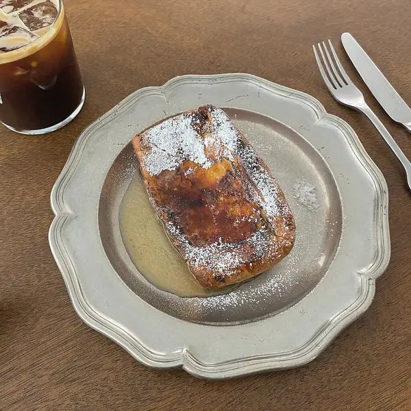 Bir parça ekmek, kahve ve mutfaktaki beyaz bir masanın üzerine bir bardak süt..