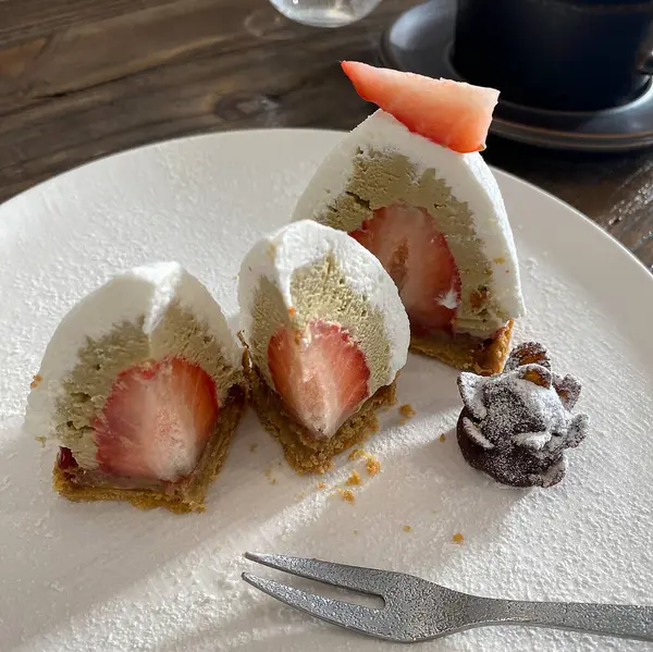 Koyu ahşap bir masada beyaz bir tabakta çilekli pasta.