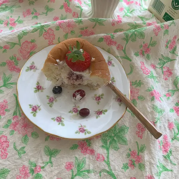 Bir fincan çayla bir parça kek ve beyaz tabakta kaşıkla bir bıçak..