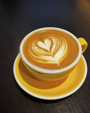 Kalp şeklinde köpüklü bir masanın üzerinde bir fincan kapuçino..