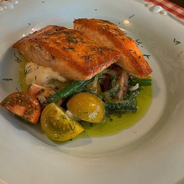 Beyaz tabakta ızgara somon bifteği ve sebze.