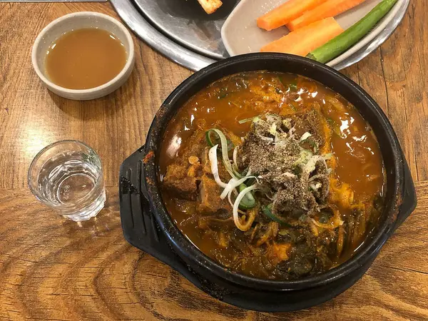 Pirinçli bir kase ve masada beyaz bir tabakla siyah bir tavuk.