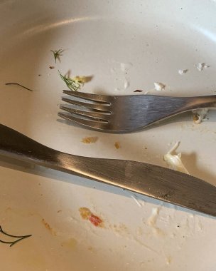 Çatal ve bıçak beyaz bir tabakta peçeteyle.