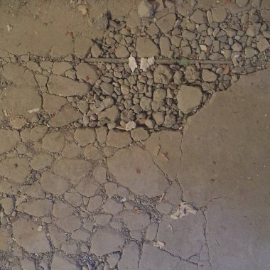 Asfalt yol yüzeyinde çatlaklar ve çizikler var.