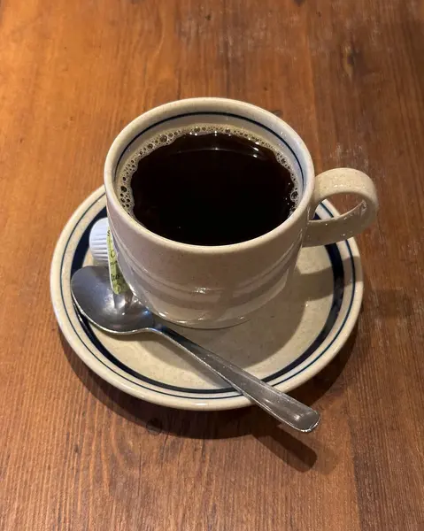 Bir fincan siyah çay tabağı ve ahşap masa.