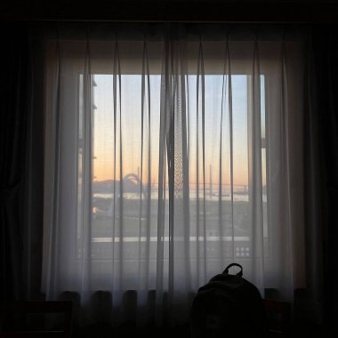 Perdeleri ve bir bardak suyu olan bir pencere.