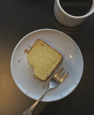 Bir fincan kahveyle beyaz tabakta bir parça kek..