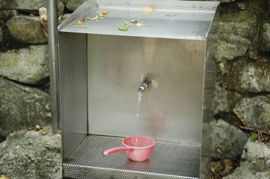 Bahçede su bulunan metal bir musluğun dikey görüntüsü.