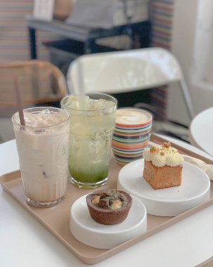 Bir fincan çay, bir bardak süt ve bir fincan kahveyle ahşap bir masada.