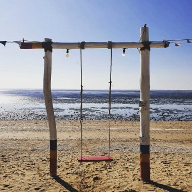 Denizde ahşap bir salıncakla bir plaj salıncağının dikey çekimi.