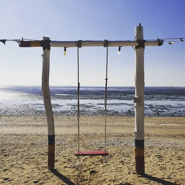 Denizde ahşap bir salıncakla bir plaj salıncağının dikey çekimi.