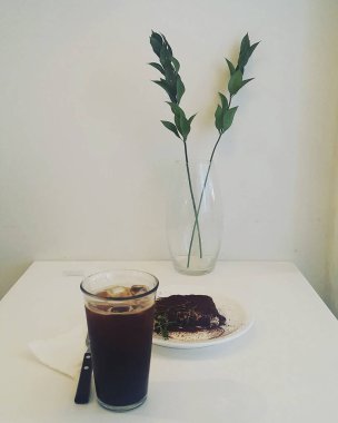 Beyaz masada bir fincan sade kahve ve kek.