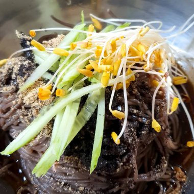 Sebzeli siyah erişte ve beyaz tabakta et.